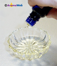 Diluting an essential oil, drop by drop, into a carrier oil.